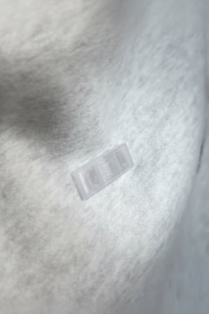 Close-up of a gray hoodie with a brand label on the chest.